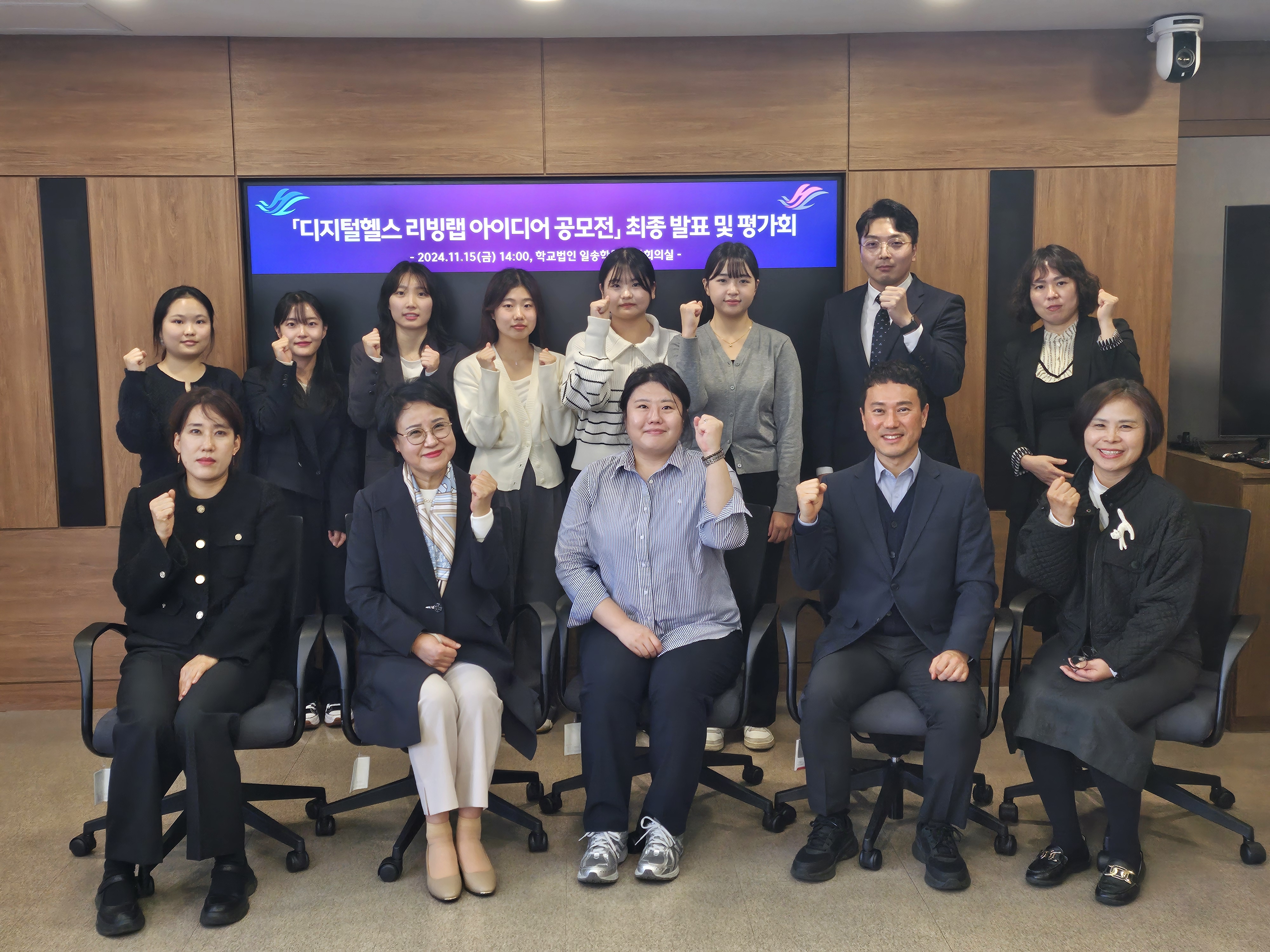 디지털헬스 리빙랩 아이디어 공모전 최종 발표 및 평가회라고 적힌 화면 앞에 교수진과 참여 학생이 단체 사진을 찍고있다.